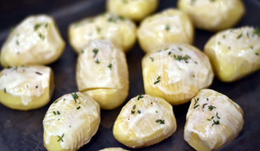 Hasselbackkartofler smurt med fedtstof og drysset med salt og rosmarin. Klar til at komme i ovnen.