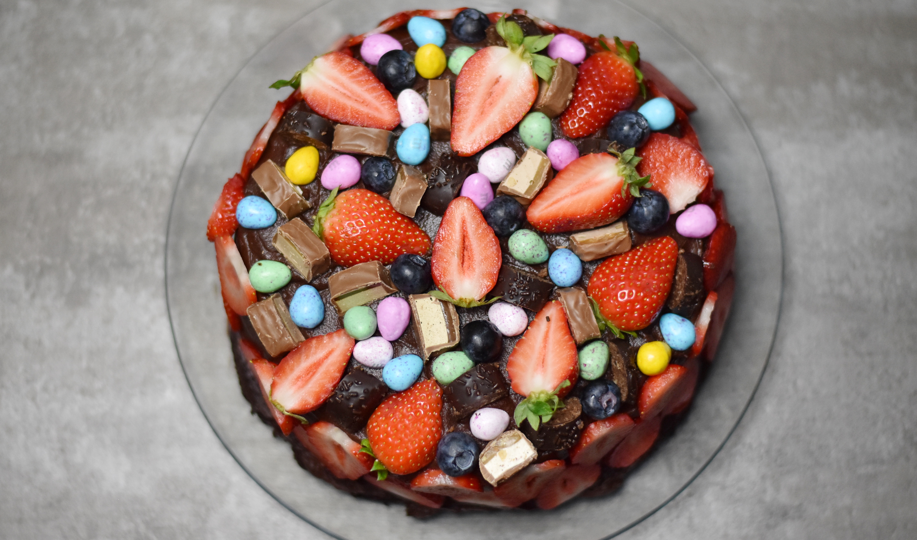 Pynt kagen med masser af bær, chokoladestykker og slik. Brug f.eks. skiver af jordbær på siderne af kagen.